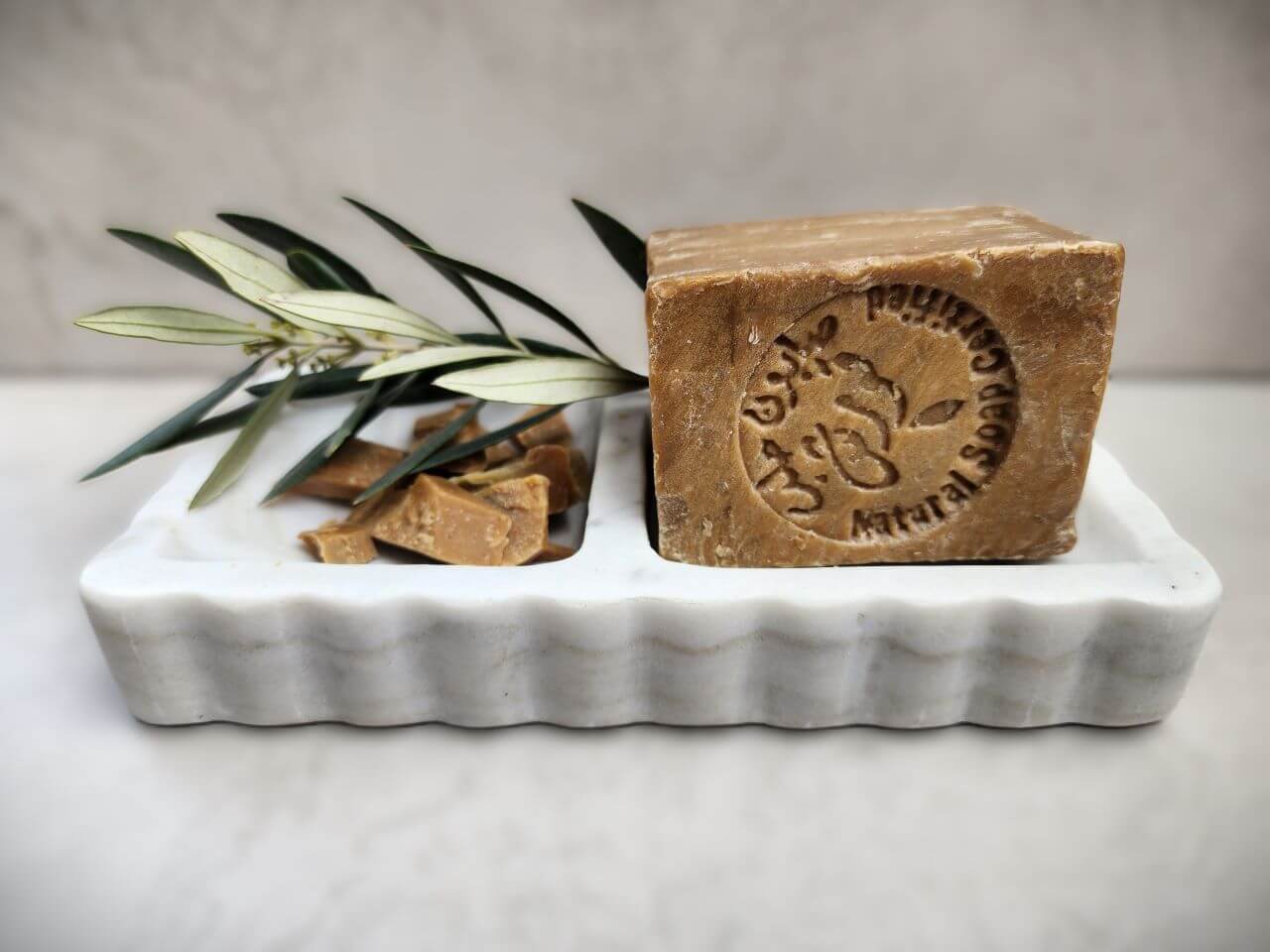 Marble soap dish with olive soap and leaves, showcasing elegant design and natural beauty for bathroom decor.