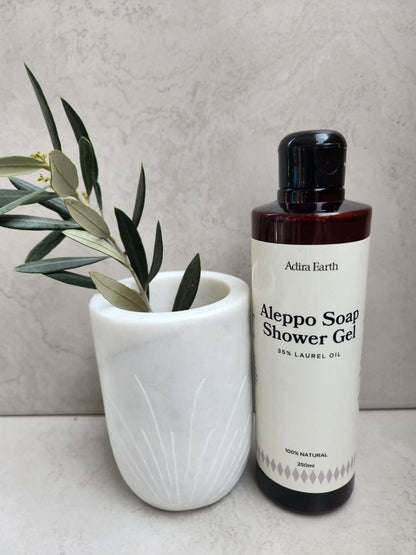 Aleppo soap shower gel with laurel oil next to a white vase with green leaves, enhancing a spa-like bathroom atmosphere.