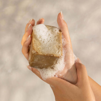 Hand holding Aleppo soap made with natural laurel oil, showcasing the traditional craftsmanship of Aleppo soap bars.