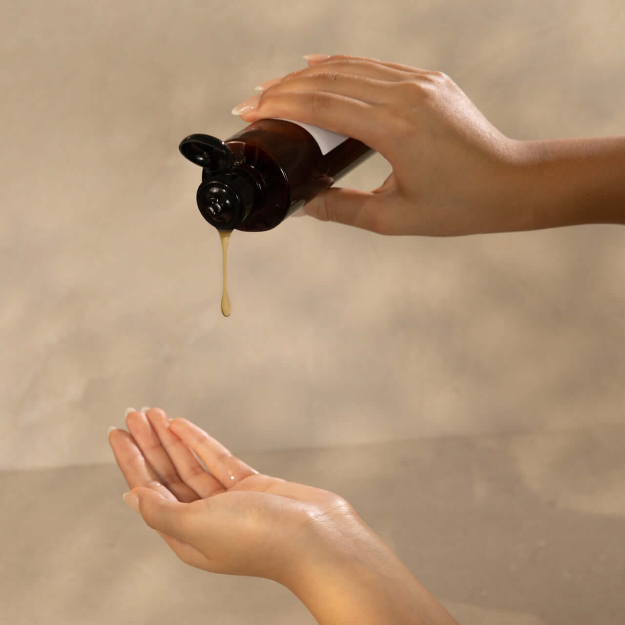 Person pouring Aleppo soap gel from a bottle into their hand for a luxurious and gentle skincare experience.